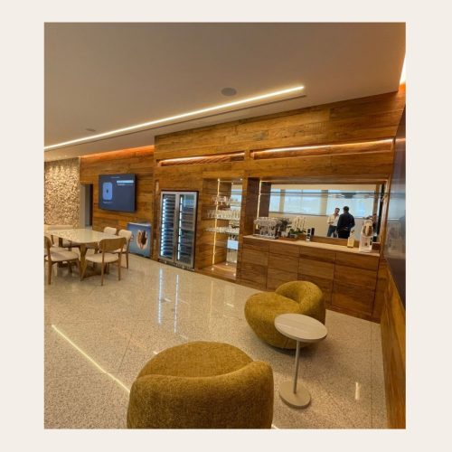 Painel corporativo em Peroba Rosa de demolição com adega climatizada, nichos iluminados e cafeteria integrada